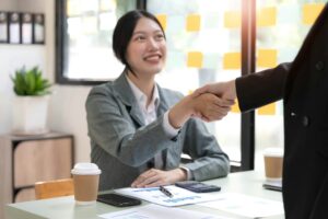 Two Asian businesswomen are shaking hands in the office. business cooperation, business dealing